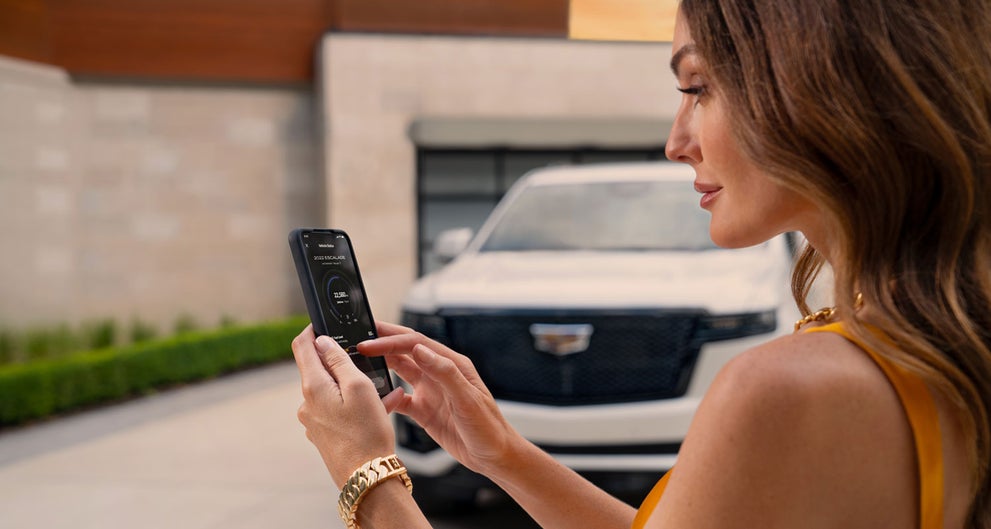 lady checking her mobile with a Cadillac vehicle background | Integrity Cadillac in Chattanooga TN